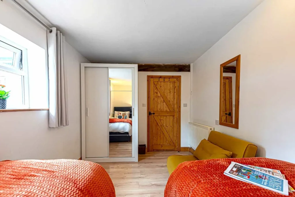 View from the twin bedroom at Fig Tree Cottage showing the mirrored wardrobe and yellow armchair