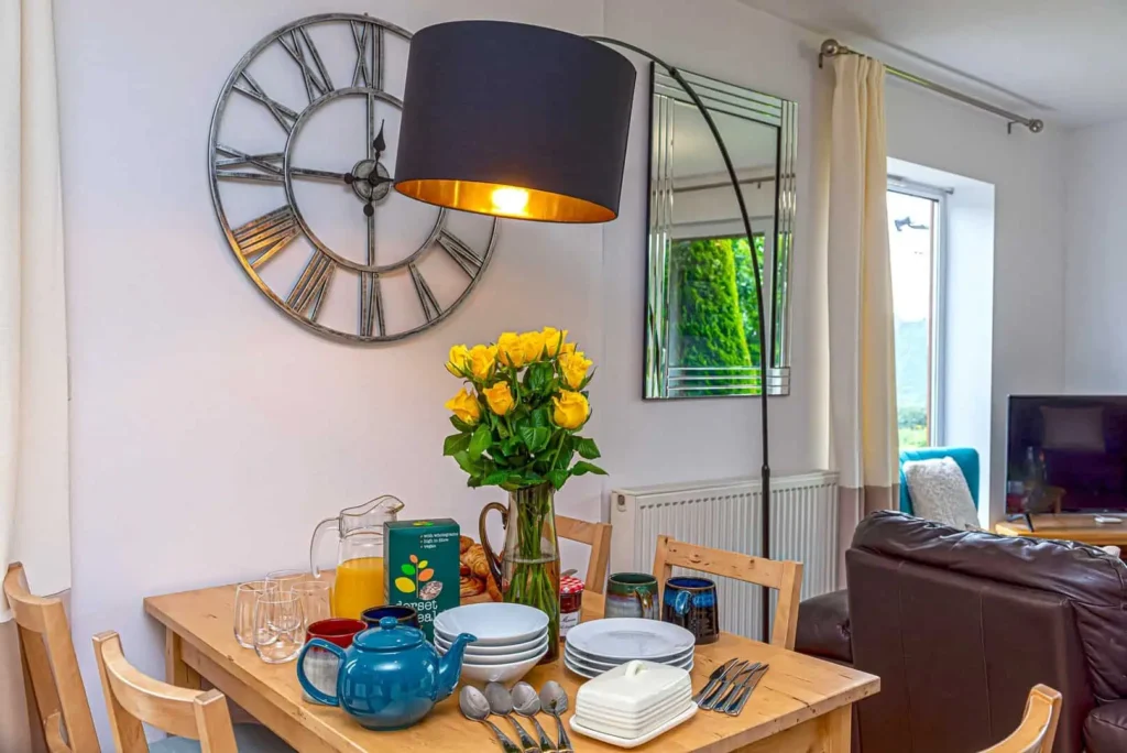 Dining table set for breakfast at Fig Tree Cottage, with a large feature clock on the wall behind