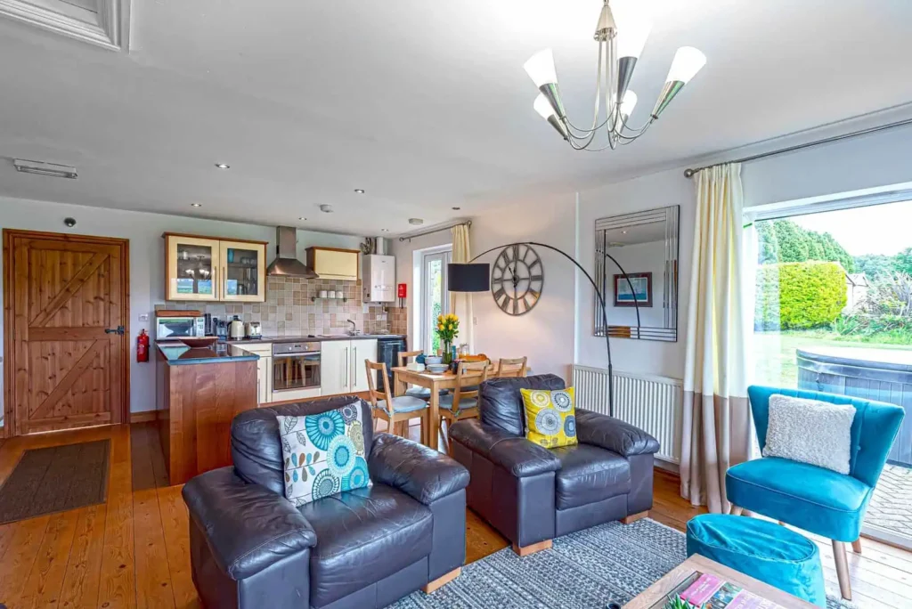 The open-plan living space at Fig Tree Cottage, showing the lounge area, dining table, and the kitchen in the background