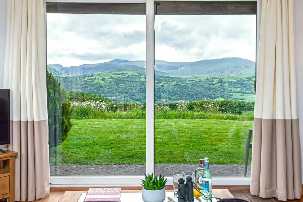 Conwy Valley Getaway | FIG TREE COTTAGE LIVING AREA LOUNGE VIEW ZOOMEED IN A clear, zoomed-in view of the Snowdonia mountains and valleys through the large patio doors of the lounge