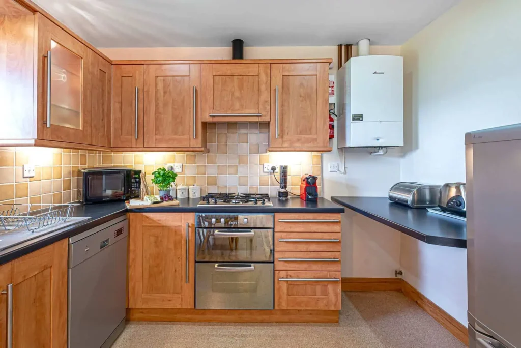 The fully-equipped kitchen at Laurel Cottage with wooden cabinets, a gas hob, oven, dishwasher and microwave