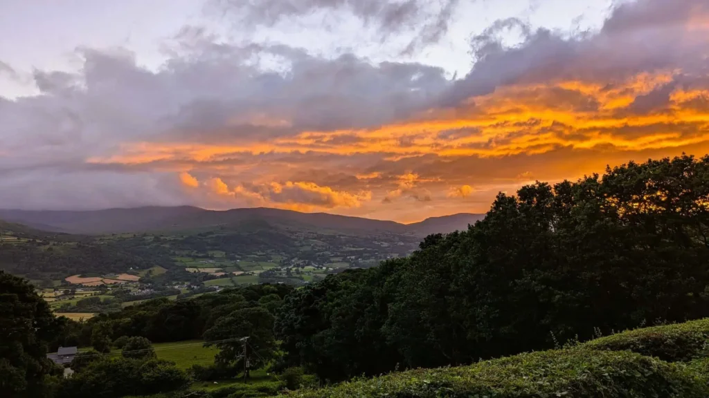 A dramatic golden sunset over the mountains and fields of the Conwy Valley in Eryri (Snowdonia)