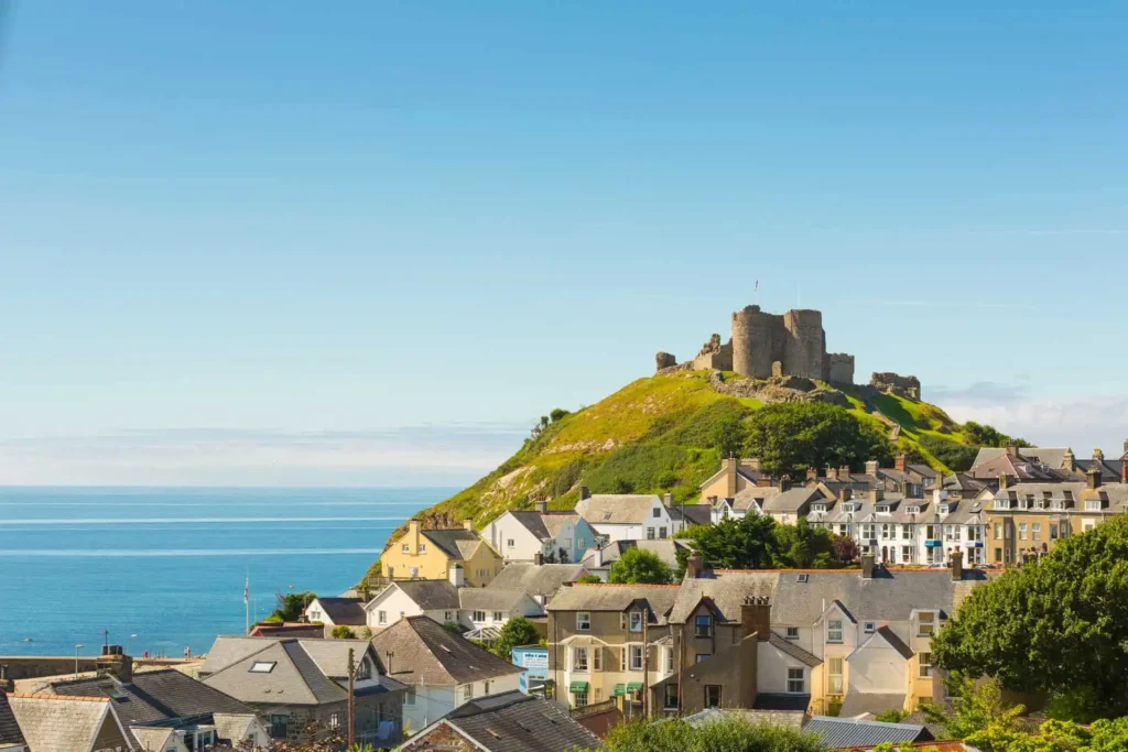Conwy Valley Getaway | 53710 criccieth castle gwynedd web optimised 1920px A distant view of Criccieth Castle ruins perched on a headland, with the rooftops of the seaside town of Criccieth in the foreground and the waters of Cardigan Bay behind the castle