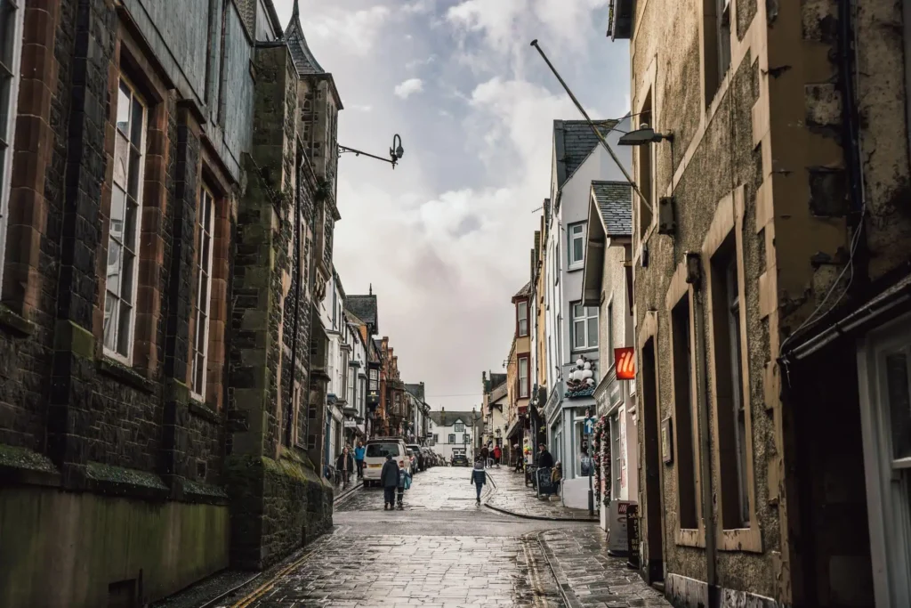 A view looking up the historic Conwy High Street, lined with traditional stone shopfronts and buildings