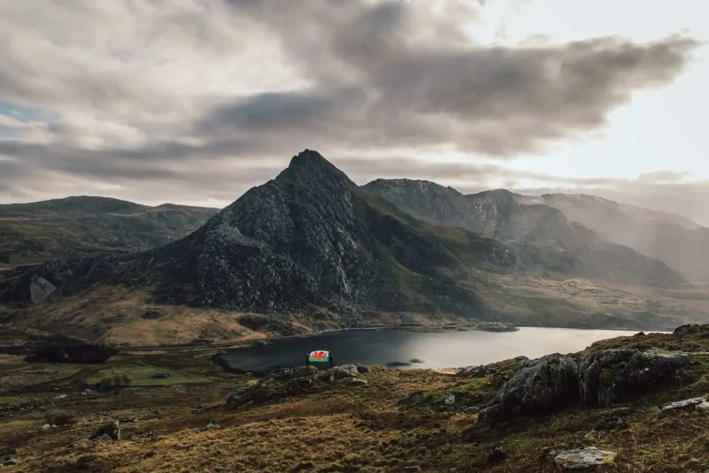 A wide view of the lake at the bottom of Ogwen Valley and the Welsh flag in the distance