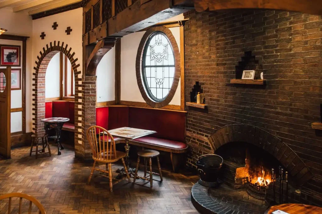Log fire and rustic wooden pub table inside The Albion in Conwy, creating a warm and cosy atmosphere - the perfect spot to relax during a quiet mid-week break