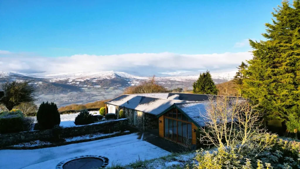 Aerial view of Fig Tree & Laurel holiday cottages on a winter's day, with snow on the ground and mountains in the background