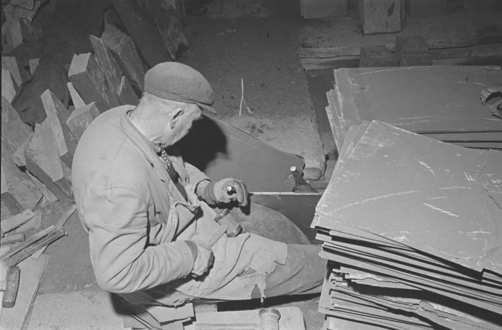 Conwy Valley Getaway | Oakley Slate Quarry Blaenau Ffestiniog 1532226 Black and white photo showing a man using hand tools to split slate tiles