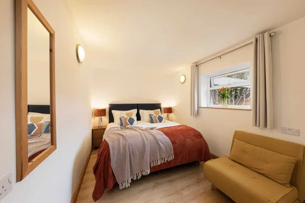 Fig Tree second bedroom showing mustard chair bed for fifth guest, with mirror