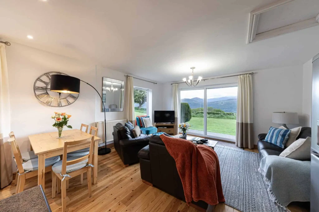 Fig Tree living area with sliding glass doors open to Conwy Valley views, terracotta throw on sofa
