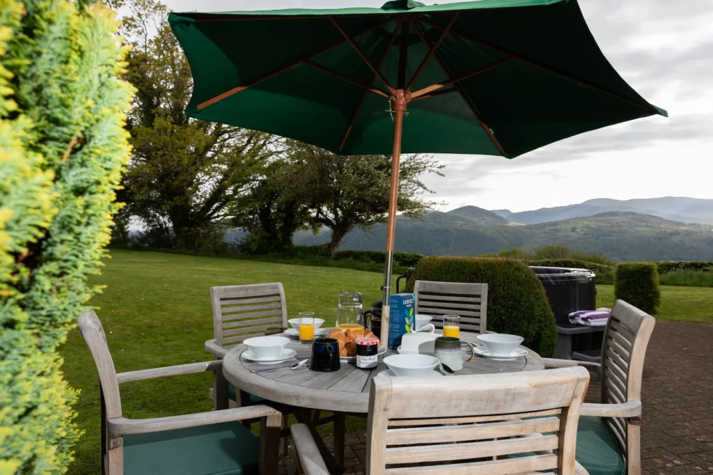 Fig Tree patio dining table set for breakfast with mountain views and hot tub to the right