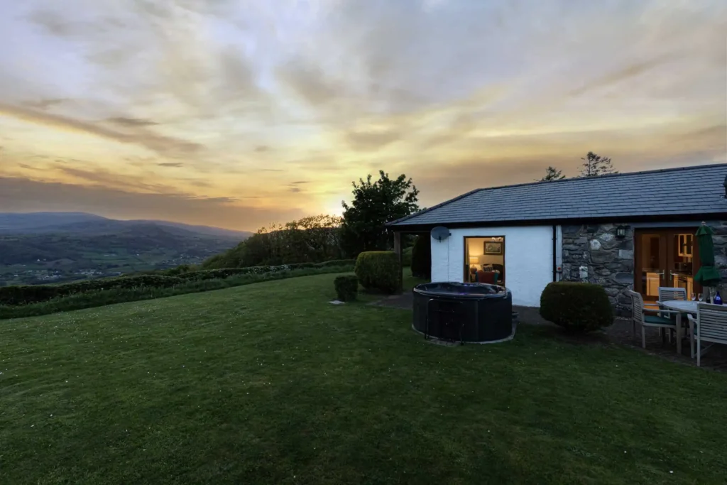 Fig Tree cottage at dusk with hot tub, garden and sunset over the Conwy Valley