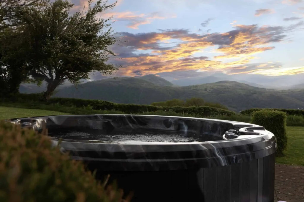 Fig Tree hot tub on patio with the Carneddau mountains under a golden sky