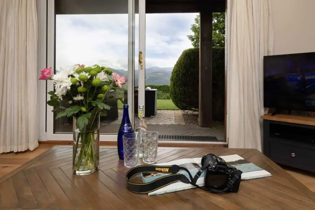 Laurel living area with sliding glass doors open, flowers and camera on coffee table