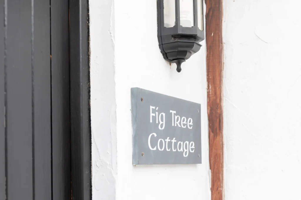 Fig Tree cottage slate sign on white wall with exterior light above