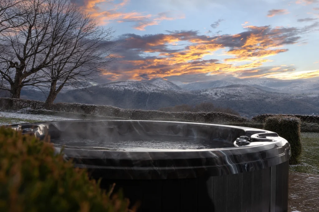 Conwy Valley Getaway | hot tub winter Private hot tub steaming under a sunset sky at the cottages